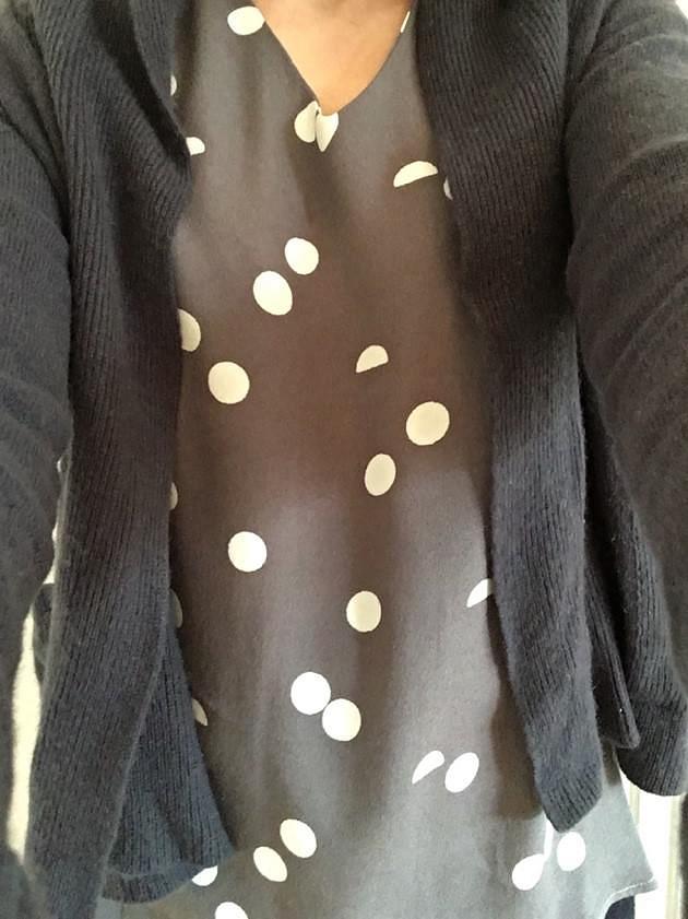 Selfie of me in a grey top with large white spots and a grey cardigan.