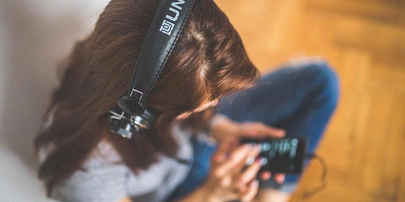 Woman wearing headphones listening to music on her phone