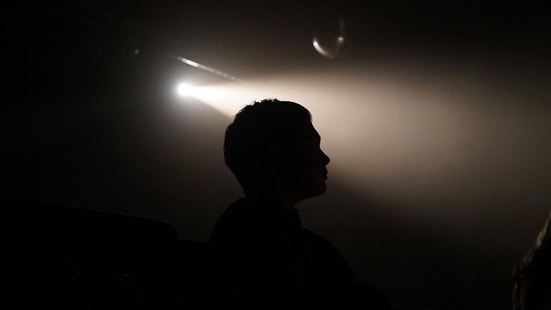 silhouette of man standing in darkness with one spotlight shining 