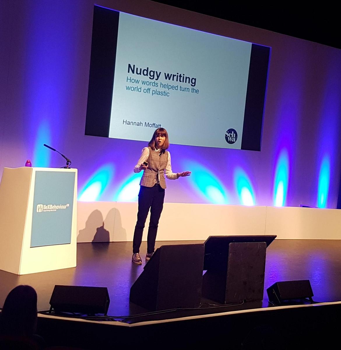 Woman presenting on stage at a conference