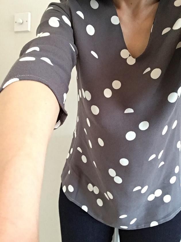 Selfie of me in a grey top with large white spots, no cardigan.