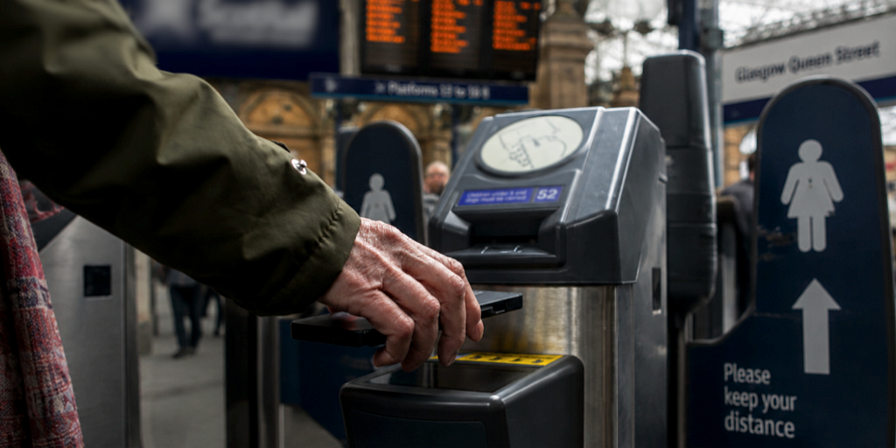 Person tapping their mobile phone using an app for barrier entry at a railway station