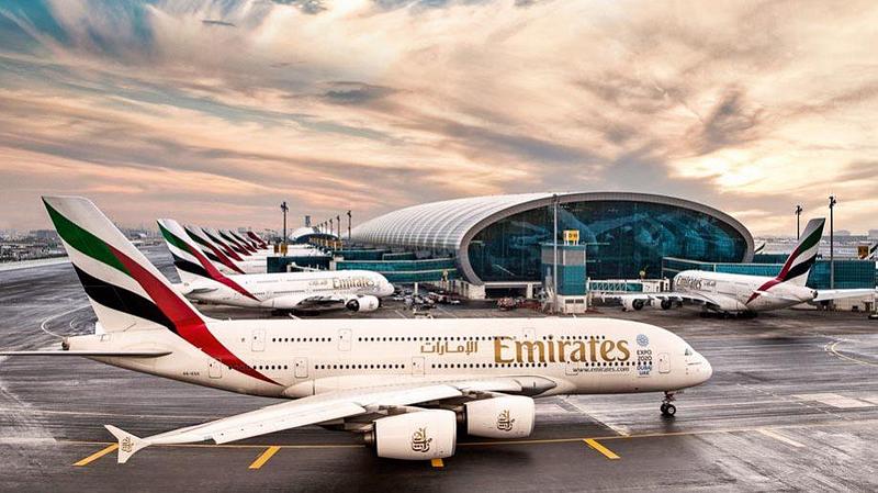 Emirates plane on the apron with Dubai airport in the background